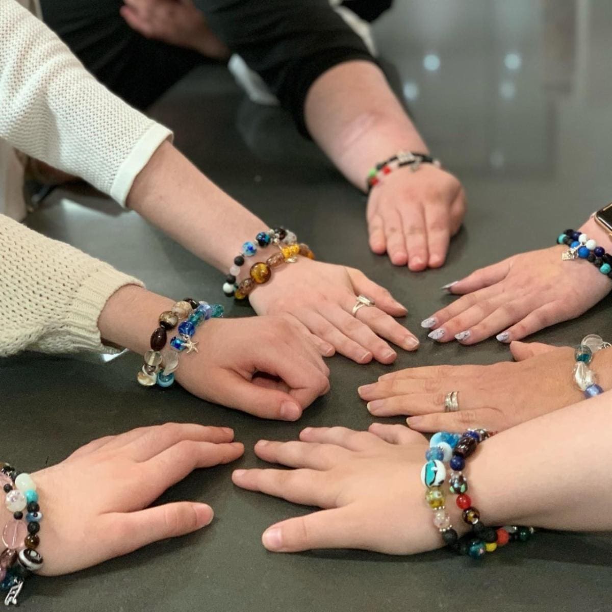 several arms together showing off colourful bracelets